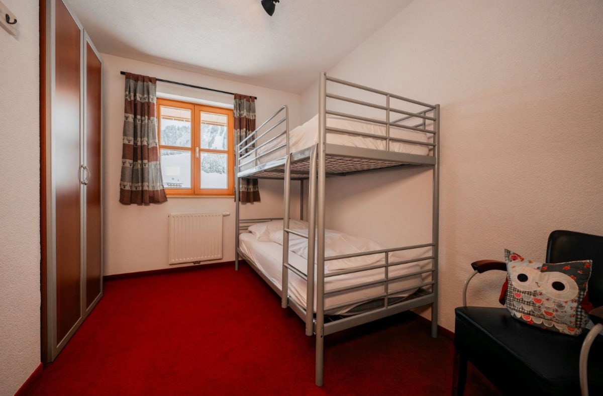 Dormitorio con literas, amplio armario de almacenamiento y silla adicional.