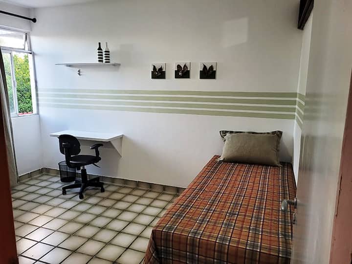 Habitación con cama individual conjugada, ventilador, vestidor, armario y un espacio de oficina 