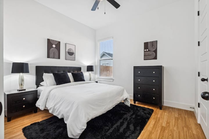 Elegantna spavaća soba s bračnim krevetom prikazuje crno-bijelu temu ukrasa, stvarajući odvažnu i modernu estetiku. 