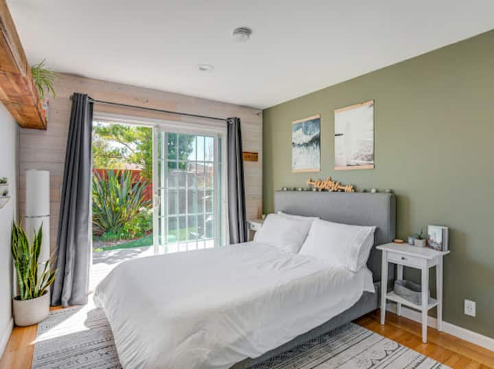 Vue d'une chambre avec un grand lit, un grand placard et une entrée privée vers la cour arrière.