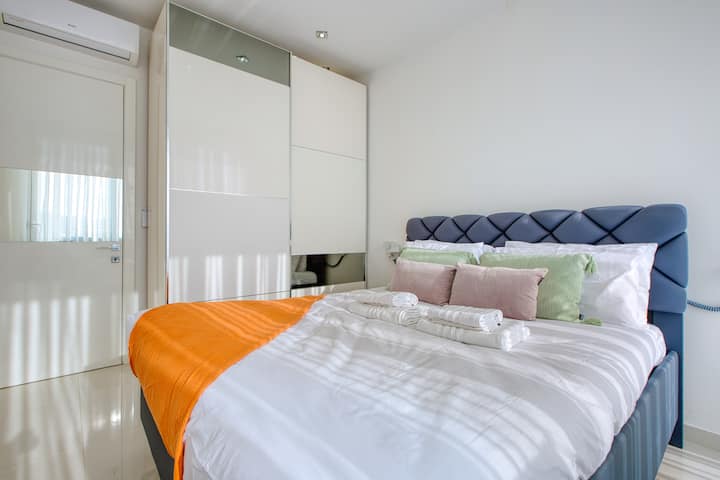 Уютна и елегантна спалня с първокласно спално бельо, меко осветление и прозорци от пода до тавана, предлагащи красиви гледки. Идеално за спокойни нощи в луксозен пентхаус Swieqi, идеален за двойки, семейства или групови почивки.