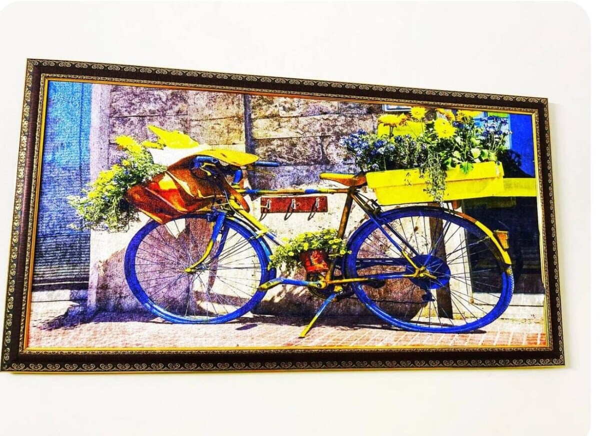 A colorful photograph displays a vintage bicycle adorned with vibrant yellow flower boxes, positioned against a textured wall. Green foliage bursts from the containers, enhancing the cheerful and lively aesthetic of the artwork.