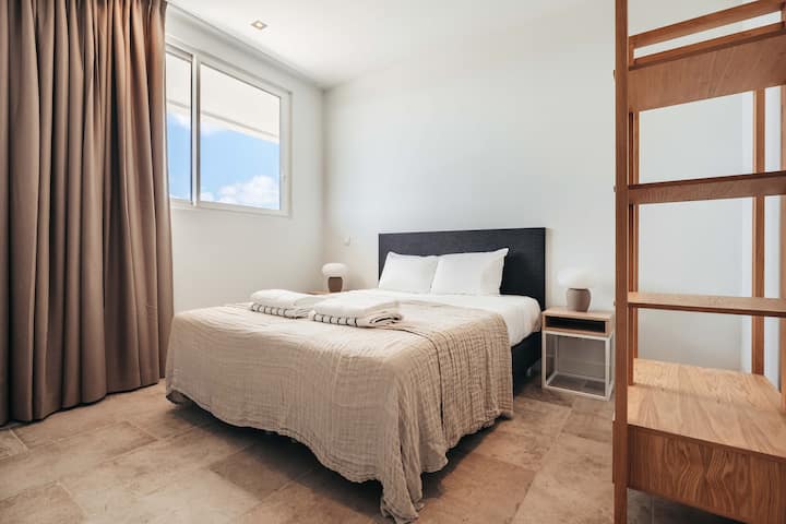 Dieses ruhige Schlafzimmer verbindet klares Design mit gemütlichen Essentials – neutrale Töne, weiche Bettwäsche und warmes natürliches Licht schaffen eine erholsame Atmosphäre, die auf Einfachheit und modernem Komfort basiert.