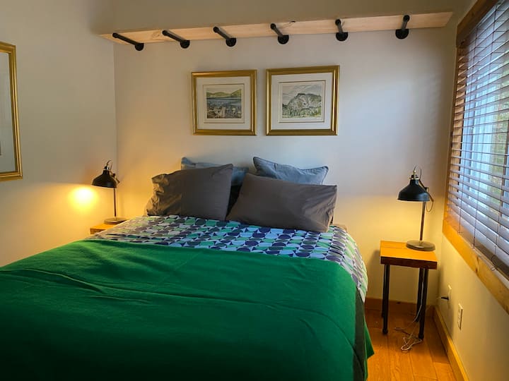 Primary bedroom at the rear of the cabin is private with Queen sized bed, new mattress topper, new duvet and large window for lots of natural light.
Glass rack opposite the bed allows for lots of clothes storage. 