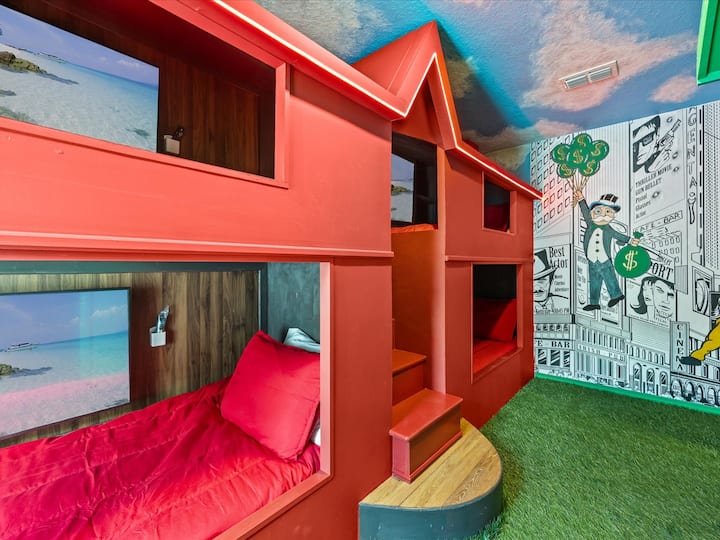 Kuća Monopoly u crvenoj boji, soba s krevetima na kat – odvažne crvene krevete na kat s ugrađenom rasvjetom za razigran prostor za spavanje.