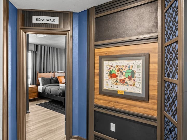 Ulaz u apartman s pogledom na šetnicu – ulaz u tematsku spavaću sobu uokviren zidnom dekoracijom s motivom šetnice iz igre Monopoly.