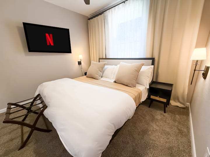 חדר שינה לאורחים 1: מיטת קינג סייז עם מצעים יוקרתיים, שמיכת כותנה לכל העונה ושמיכת קטיפה. תיהנו מוילונות האפלה, פמוטים מעומעמים, שידות לילה משובצות וטלוויזיית Roku לנוחות אולטימטיבית.