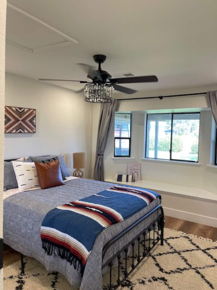 Western‑inspired haven: Cowboy‑chic queen bed with rugged‑style linens, a bay‑window lookout to the backyard, crystal‑inset ceiling fan, dimmable lights, blackout curtains—and a roomy closet for all your boots and hats.