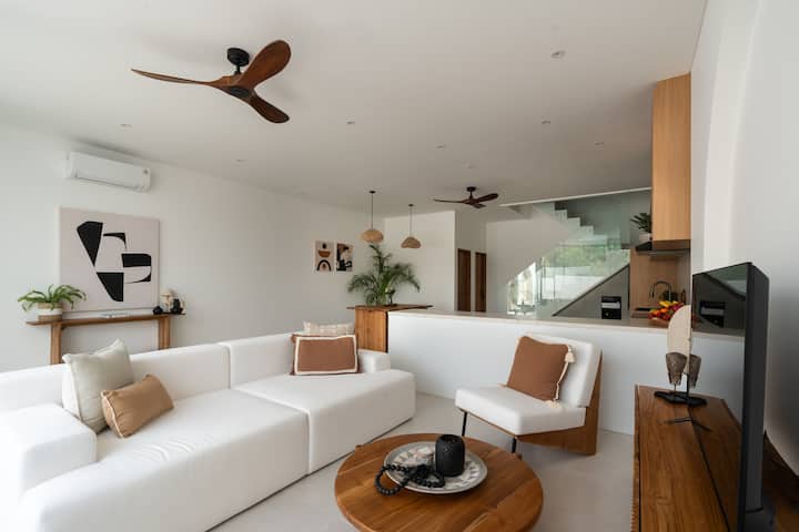 Светло и модерно жилищно пространство с уютен секционен диван, топли дървени акценти и минималистичен декор за пълна релаксация.