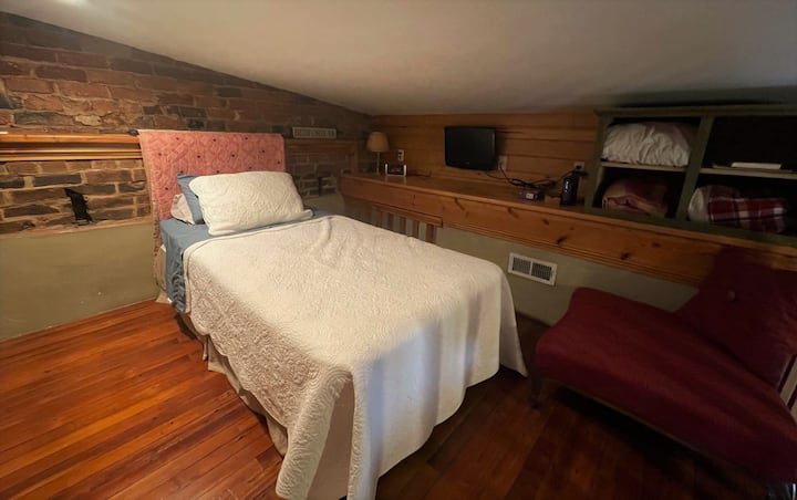 เตียงเดี่ยวที่อบอุ่นในห้องนอนใต้หลังคาที่มีสมาร์ททีวีและโรคุ