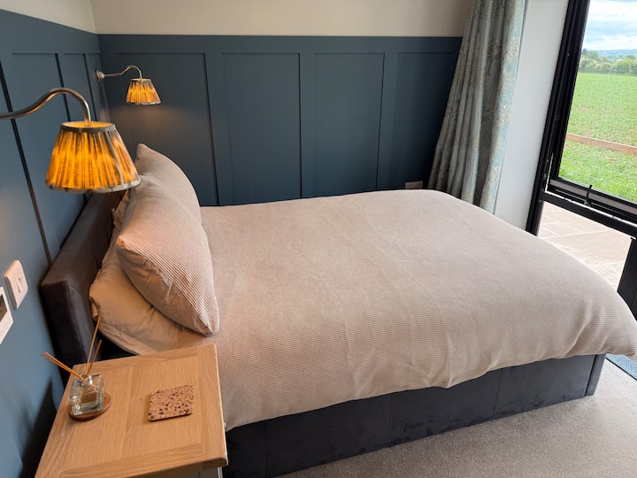 Dormitorio dos con cama doble, mesitas de noche, luces acogedoras y cómoda y barandilla colgante fuera de la vista