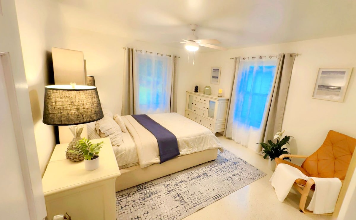 Este tranquilo segundo dormitorio incluye una cama tamaño queen, ropa de cama suave de Macy's, cortinas opacas y dos ventanas con transparencias, una con vistas al patio trasero cubierto de hierba. El ventilador de techo, el vestidor, las mesitas de noche y un sillón agregan comodidad. 