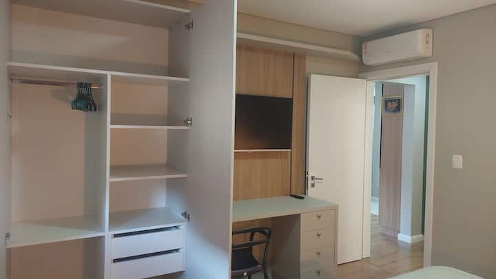 No quarto ainda roteiro com repartições de cabides,  prateleiras e gavetas.