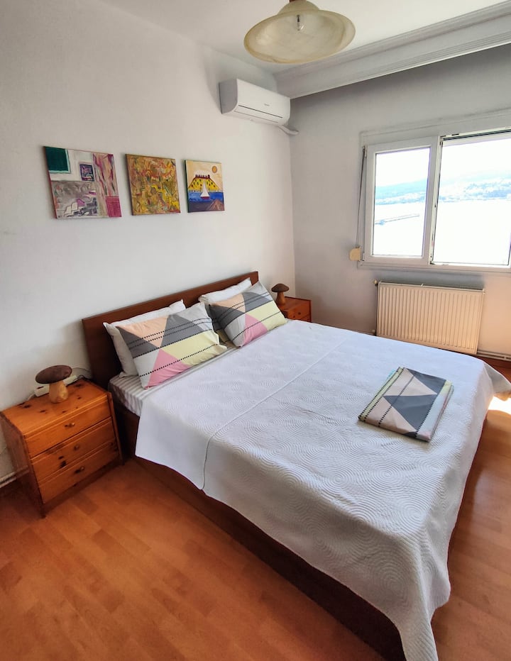 Dormitorio principal luminoso con vistas al mar, cama doble y aire acondicionado: despierta con la luz del sol y la serenidad.