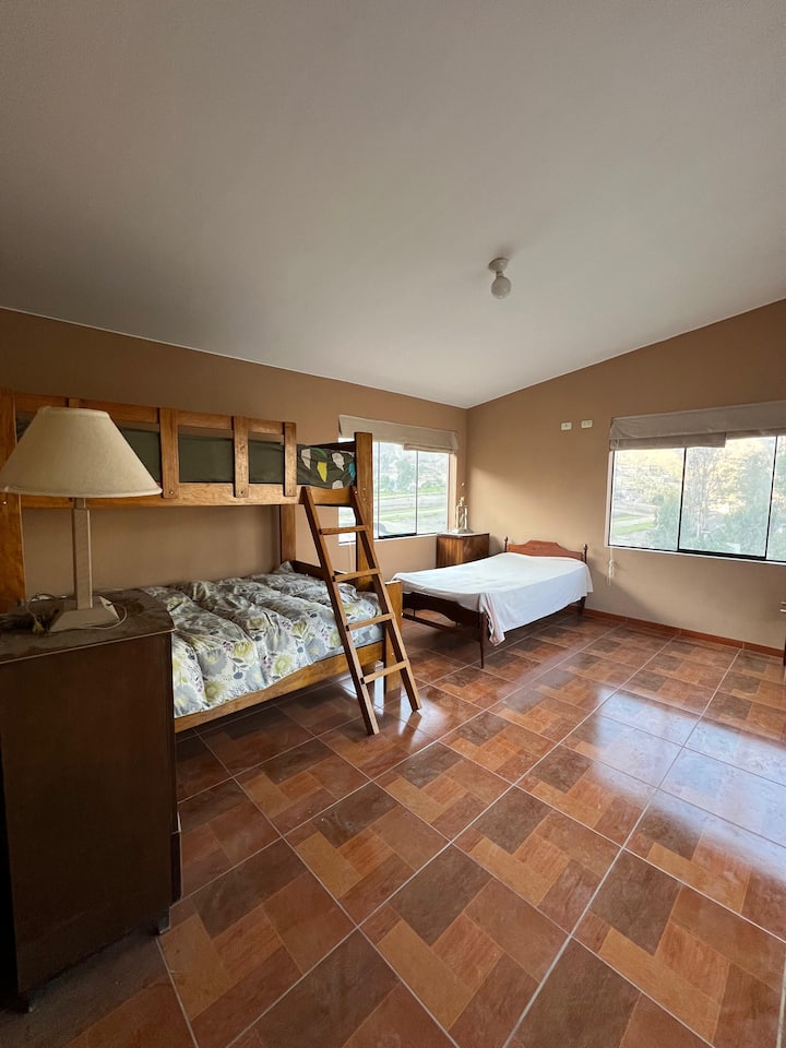 Tercera recámara equipada con dos camas y amplios ventanales que inundan el espacio de luz natural. Un ambiente fresco y confortable, ideal para asegurar el descanso de su grupo en un entorno privado, impecable y acogedor.