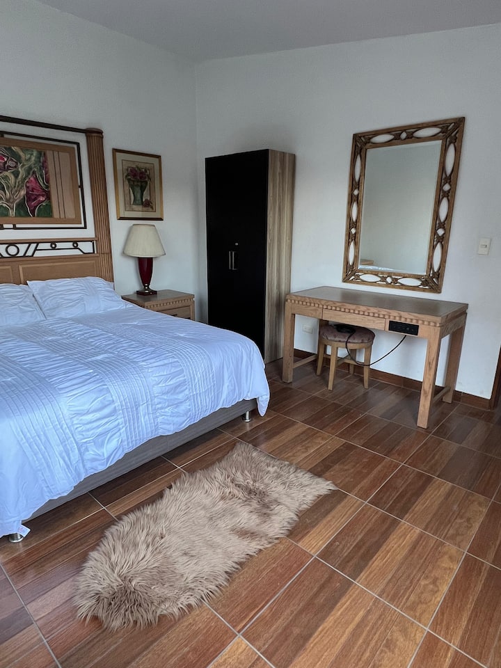 Espaciosa habitación principal con cama Queen y ventanales panorámicos que ofrecen una vista inigualable al valle. Un refugio de paz diseñado con detalles rústicos y luz natural para garantizar un descanso reparador en total privacidad.