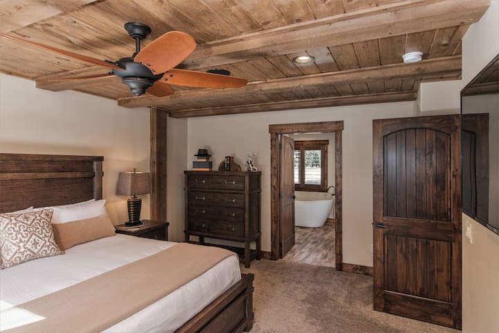 Suite principal con cama tamaño king y cálidos acabados en madera. Acceso directo al baño privado con bañera y ducha a ras de suelo para una experiencia de spa.