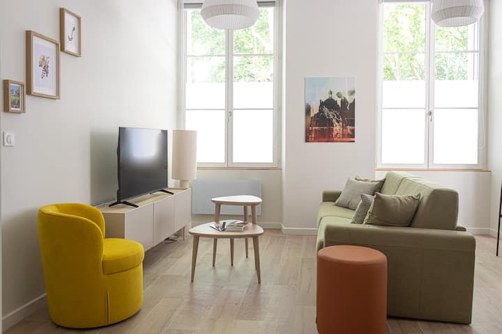 غرفة معيشة مشرقة بأسلوب عصري مع أثاث مصمم وأريكة مريحة ومنطقة أنيقة لتناول الطعام. مثالية للاسترخاء أو مشاركة لحظة ودية في أجواء أنيقة ودافئة.