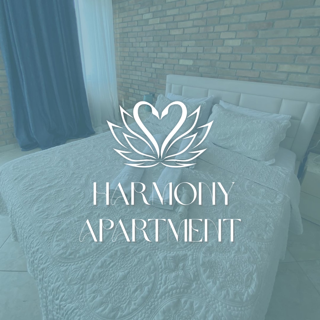 A spacious sleeping area is seen with a light-colored quilted bedspread covering the large bed. Soft blue curtains frame a window, complementing the warm tones of the exposed brick wall. Natural light bathes the room, creating a serene ambiance.