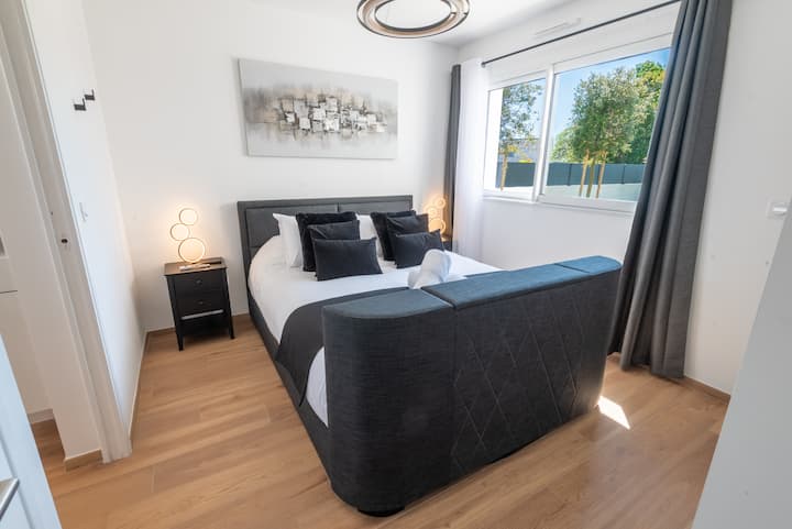 Suite parentale élégante avec salle de bain privative, dressing sur-mesure et télévision escamotable intégrée au lit.