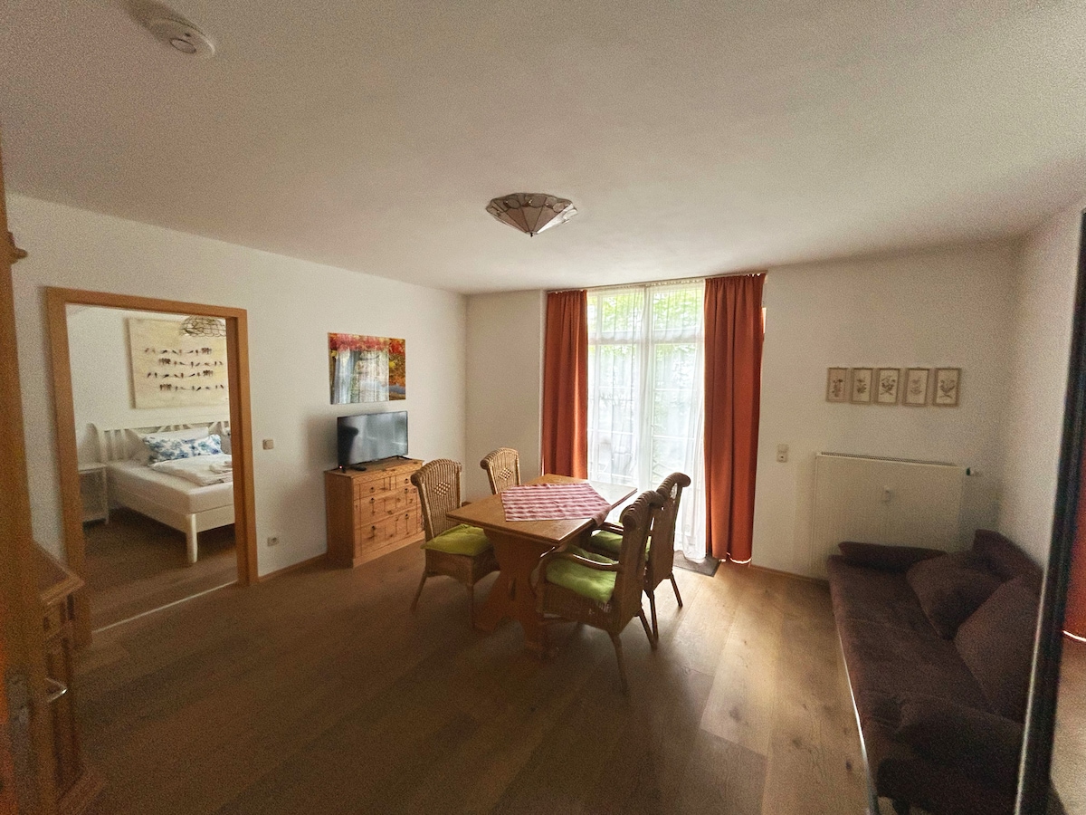 Svetlá obývacia izba s prístupom na terasu, útulnou rozkladacou pohovkou, jedálenským stolom pre 4 osoby a televízorom s plochou obrazovkou. Veľké okná poskytujú dostatok svetla a nábytok z prírodného dreva vytvára útulnú atmosféru. Spálňa je priamo priľahlá a prístupná.
