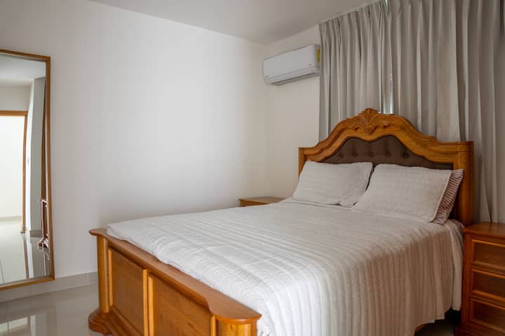 Habitación secundaria con cama queen, aire acondicionado y colchón de alta calidad para un descanso placentero