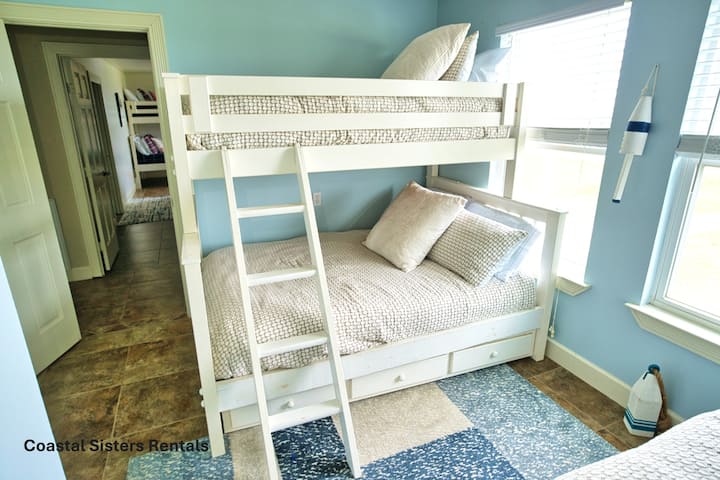 Piramidevormig stapelbed met een volledig bed onderaan, een eenpersoonsbed bovenaan en extra opbergruimte eronder