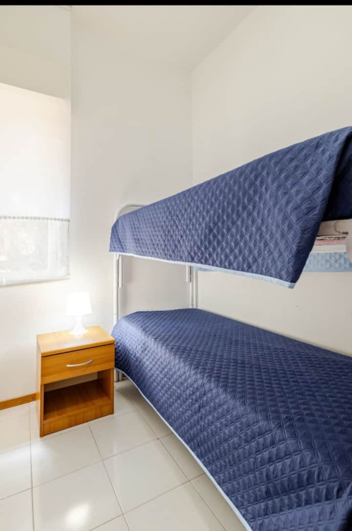 Acogedora habitación con litera práctica, perfecta para dos personas en un entorno relajante. La ventana deja entrar luz natural y una ventilación agradable, mientras que el ventilador garantiza un clima fresco y cómodo.