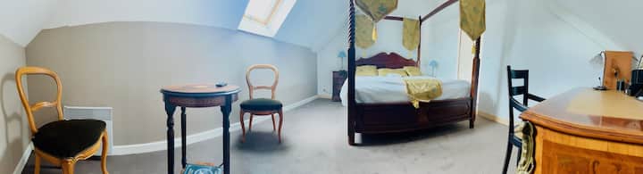 Chumba kikuu cha kulala chenye kitanda na sehemu ya ofisi yenye mabango manne. 