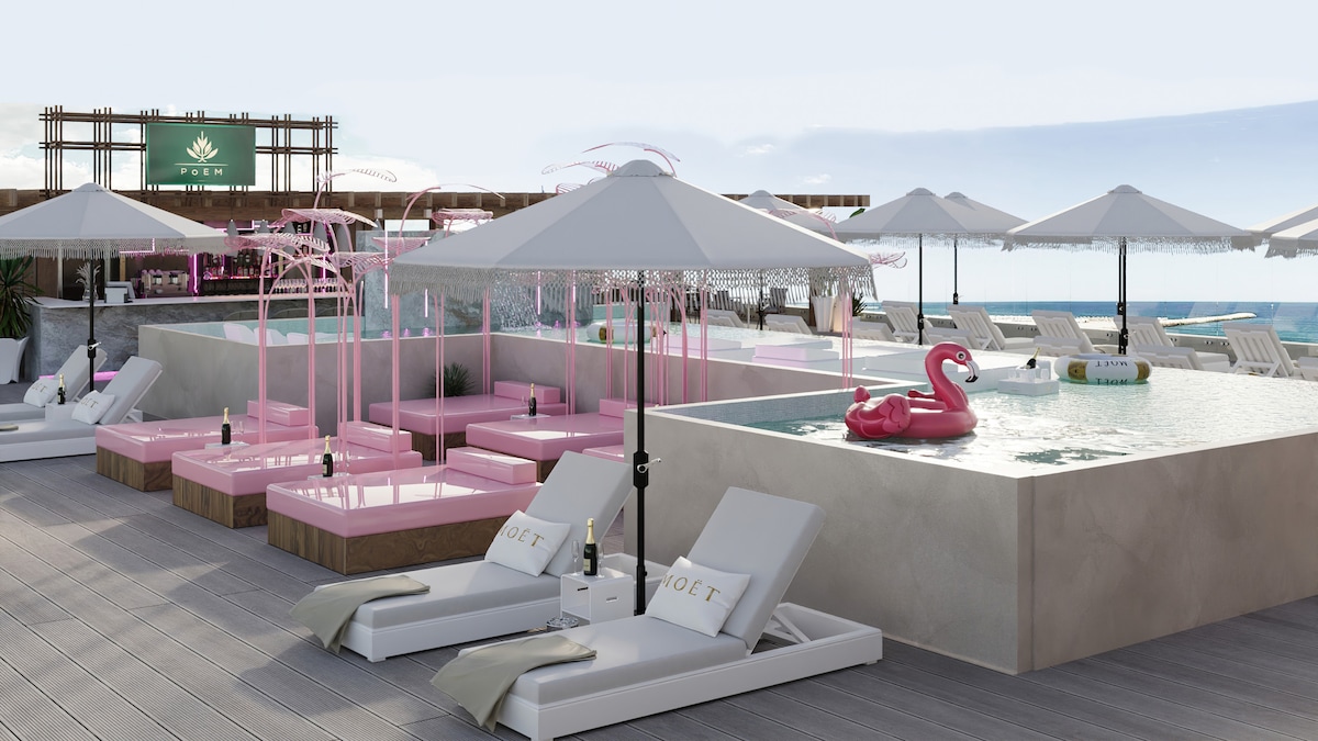 The rooftop area features a selection of pink lounge beds with umbrellas, surrounded by elegant cabanas. An inviting infinity pool is highlighted, complemented by a whimsical flamingo float. Relaxation spaces are provided with white sun loungers, creating a serene atmosphere overlooking the horizon.
