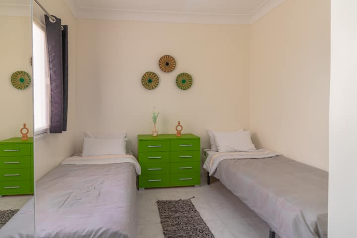 غرفة نوم عملية ومشرقة مع سريرين مفردين، مثالية للأطفال أو الأصدقاء المسافرين معًا، في جو منعش وملون