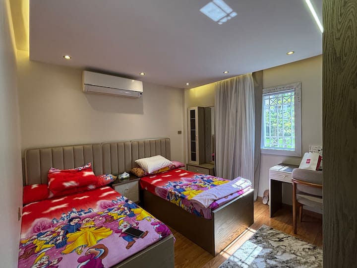 ห้องนอนที่ 3 มีหน้าต่างม่านบังแสงและวิวสวนกว้าง มีผ้าเช็ดตัว ผ้าปูที่นอน ผ้าคลุมเตียง และผ้าห่ม