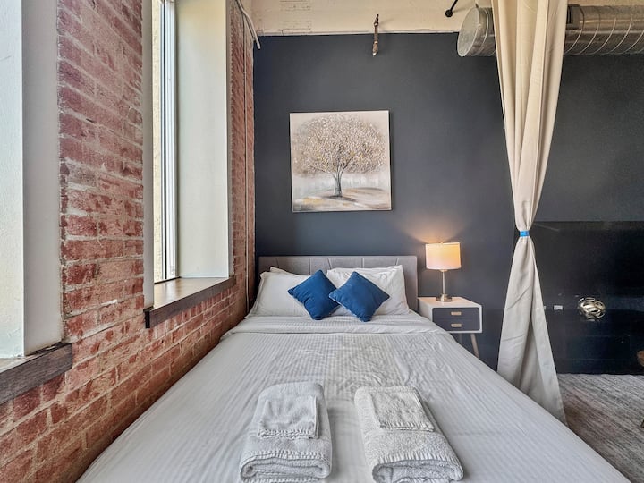 Cozy bedroom with a comfortable bed, fresh linens, and large windows that bring in natural light throughout the day.