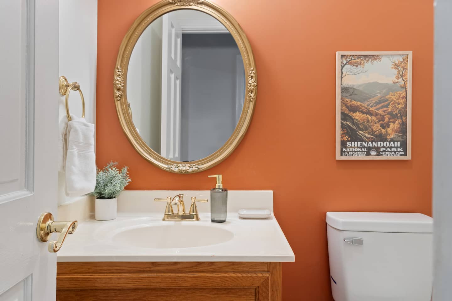Powder room with round mirror and orange walls