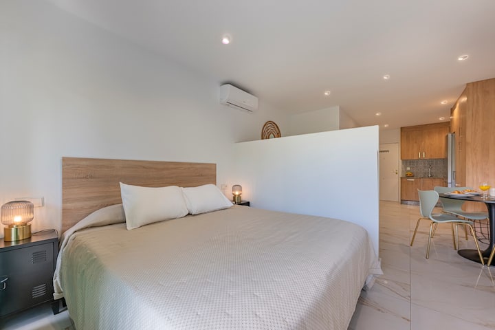 חלל שינה מואר היטב ליד היציאה למרפסת, יש מיזוג אוויר, שני שולחנות קלים וחלל אחסון