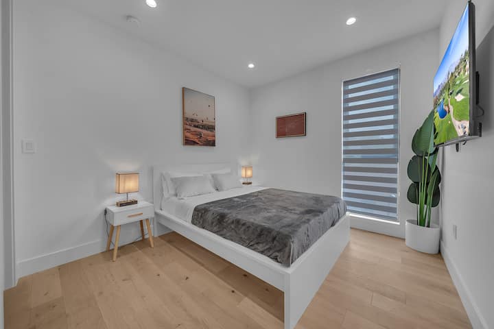 Dormitorio con cama queen, televisor inteligente y acabados modernos, ideal para un descanso profundo.