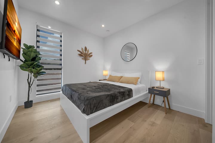 Dormitorio con cama queen, televisor inteligente y acabados modernos, ideal para un descanso profundo.