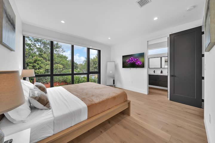 Dormitorio con cama queen, televisor inteligente y acabados modernos, ideal para un descanso profundo.