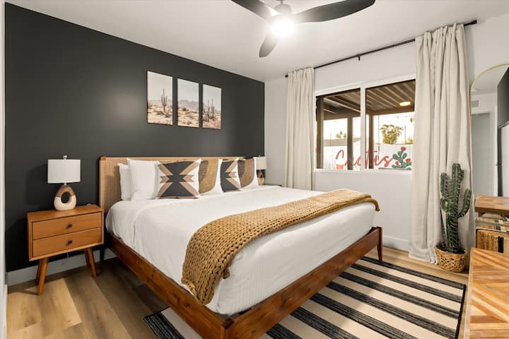 Ova spavaća soba ima zid u dramatičnoj boji i upečatljive fotografije pustinje.