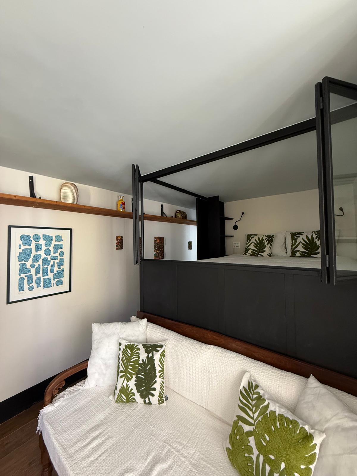 سرير مزدوج في وضع مرتفع، مع سلم وصول ساحر وأجواء مريحة.