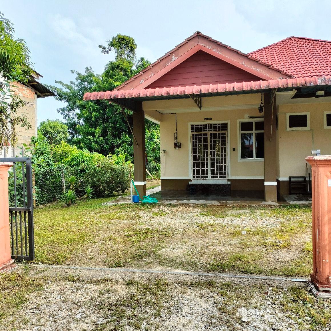 The exterior of the home features a covered porch with a red-tiled roof, surrounded by a well-maintained lawn. The entrance is framed by a gated entryway, with lush greenery visible in the background, creating a serene atmosphere.