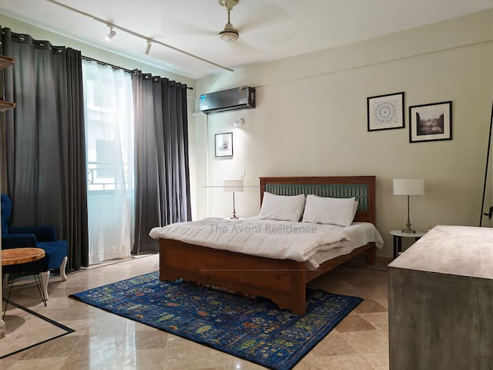 Un moderno letto queen-size con una bella testiera tradizionale in metallo color foglia di tè, che rompe la monotonia dei colori neutri che lo circondano. Un moderno tappeto tradizionale si abbina alle tonalità di blu della stanza.