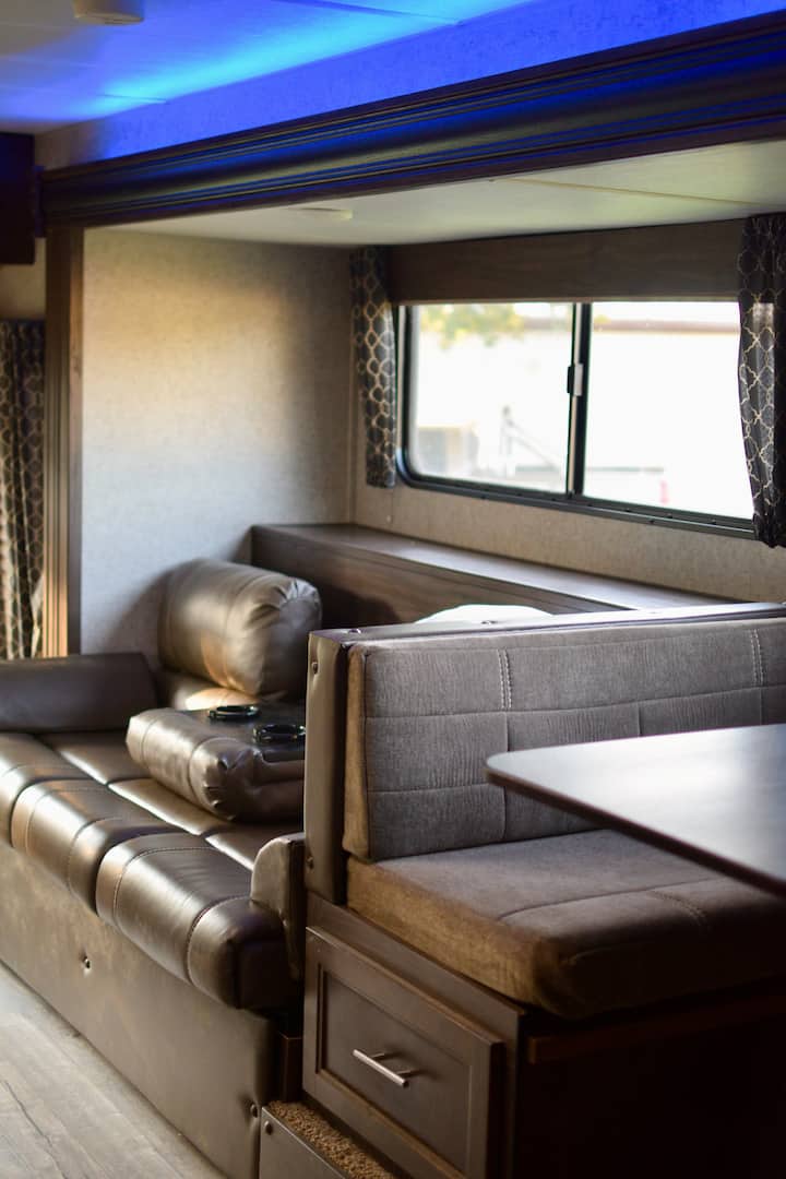 Kožený gauč sa rozkladá na posteľ v plnej veľkosti. LED osvetlené skladacie držiaky na poháre na gauči. Jedálenský stolík pre ďalšie miesta na sedenie.