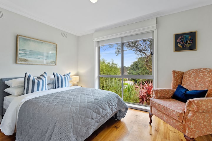 Druga spavaća soba s pogledom na zeleni vrt ima bračni krevet, naslonjač i mekani jastuk koji poziva na opuštanje.