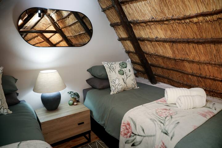 รูปถ่ายระยะใกล้ของโต๊ะข้างเตียงและเตียงในห้องใต้หลังคา