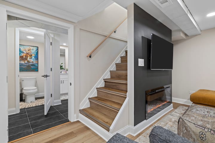 Eneo hili la kati la ngazi ya chini linaunganisha sebule yenye starehe na bafu na sehemu za kuishi za ghorofa ya juu. Mchoro wa meli uliokusanywa kwa mkono unaongeza sifa na mpangilio hufanya iwe rahisi kuvinjari sehemu za pamoja huku ukiwapa wageni nafasi ya kuenea.