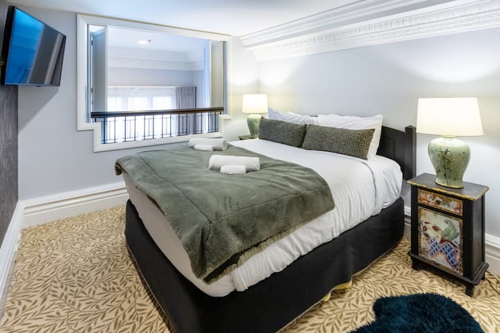 Брачна спална соба со гардероба, телевизор и бања во сопствен стил