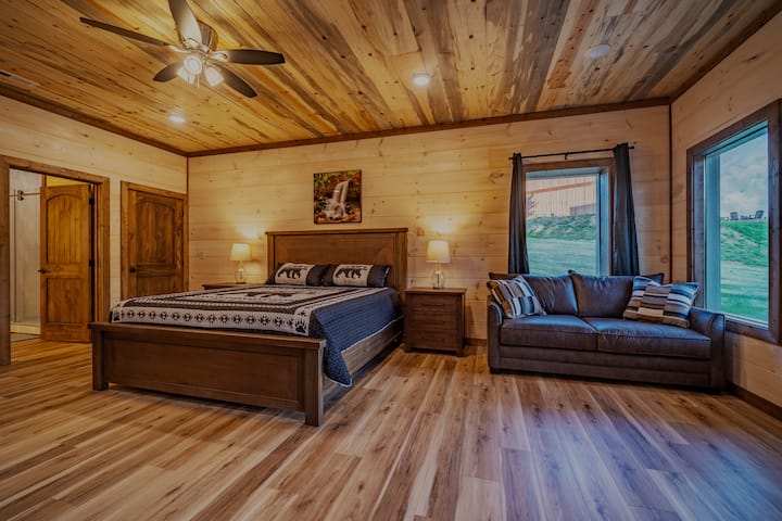 חדר שינה ראשי בקומה התחתונה עם חדר שינה צמוד, ספה נפתחת, קמין חשמלי וטלוויזיה חכמה 55 אינץ'. 