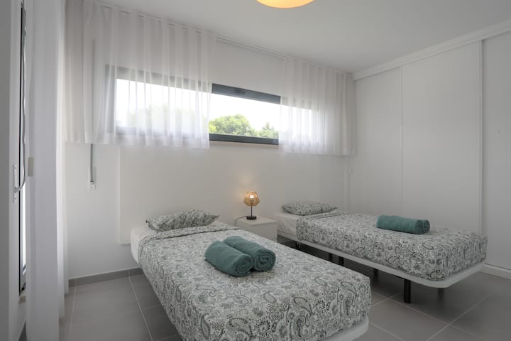 Dva jednostruka kreveta (mogu se spojiti) u prizemlju s roletama, klima-uređajem i velikim ormarom u pozadini.