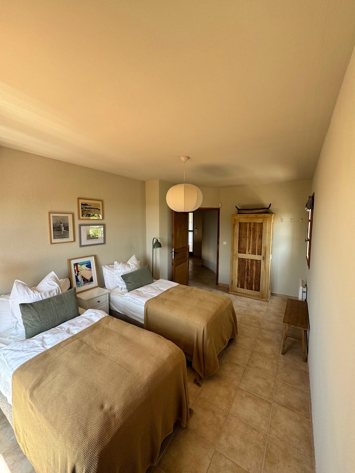 Dve pohodlné samostatné postele s klimatizáciou, ktoré vedú na terasu na poschodí s výhľadom na more. 
Veľká kúpeľňa so sprchovacím kútom je na tom istom poschodí (kúpeľňa 1).